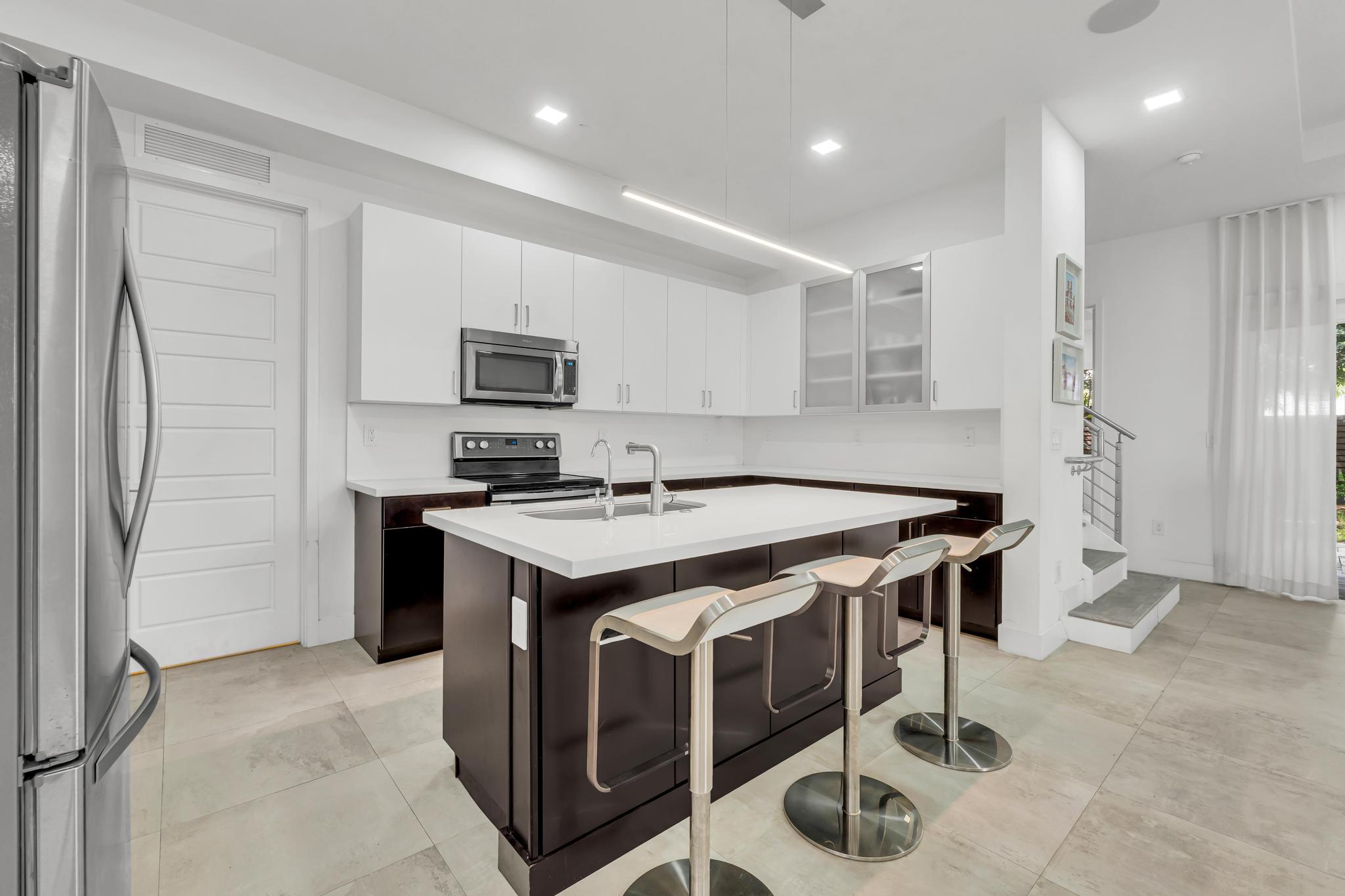 Modern kitchen with center island in Venetian Parc residence Cocina moderna con isla central y electrodomésticos en casa de Miami