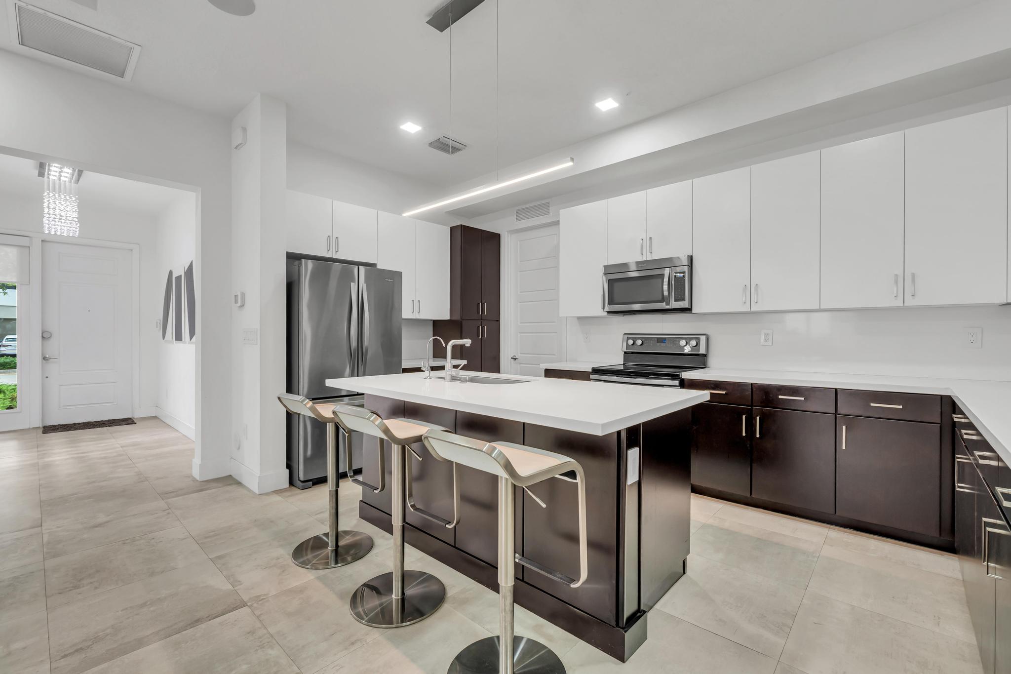 Modern kitchen with center island in Venetian Parc residence Cocina moderna con isla central y electrodomésticos en casa de Miami