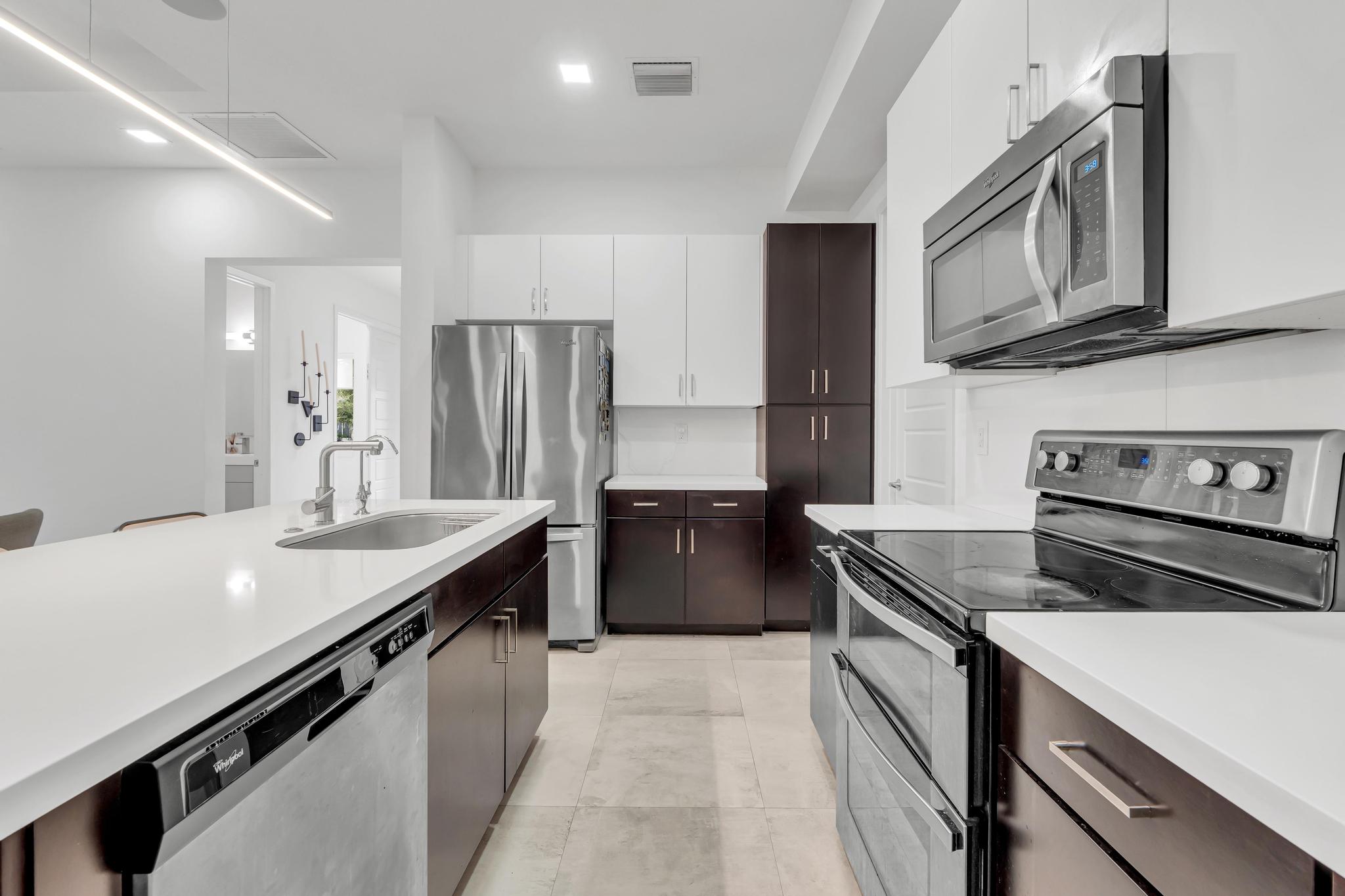 Modern kitchen with center island in Venetian Parc residence Cocina moderna con isla central y electrodomésticos en casa de Miami